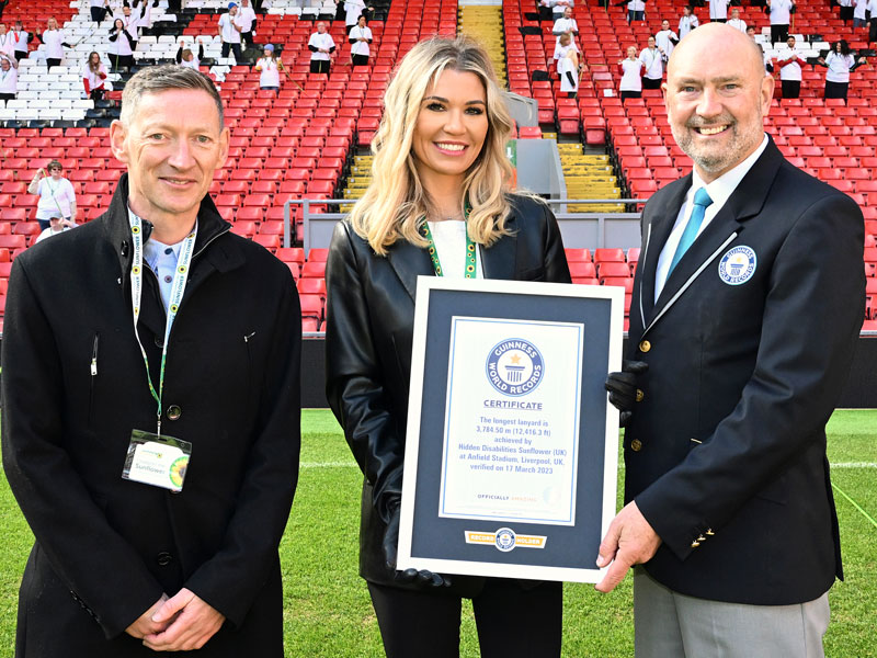 L to r: Paul White, Christine McGuinness and Glenn Pollard holding the Guinness World Records certificate for the longest lanyard at Anfield on 17 March 2023