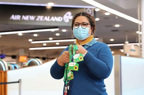A masked female member of Auckland airport staff holds Sunflower lanyards